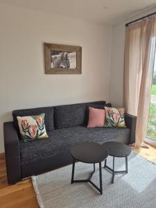 un soggiorno con un divano nero e un tavolo di Ferienwohnung NoEl a Dietmannsried