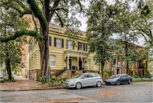 サバンナにあるSavannah Garden on Historic E Jones Stの黄色い家の前に停められた車2台