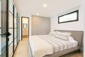 a white bedroom with a bed and a bathroom at Casco Viejo 2BR Loft - Rooftop Pool Gym & Balcony in Panama City +13 photos