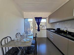een keuken met een tafel met borden en glazen erop bij Casa 02 com 2 quartos, churrasqueira 15min centro in Foz do Iguaçu