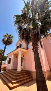 een roze gebouw met een palmboom ervoor bij Villa Santa Bárbara en Isla Canela in Isla Canela