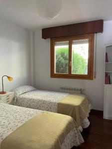 a bedroom with two beds and a window at El jardín de Max, apartamento céntrico con jardín privado y parking in Comillas