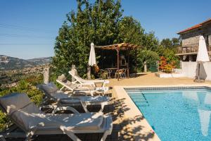 a swimming pool with chairs and a table and a house at Leira da Cruz Grande in Castelo de Paiva