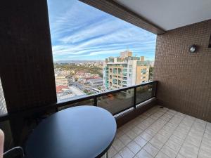 Un balcón con una mesa y vista a una ciudad. en Flat no Alto da XV, en Curitiba