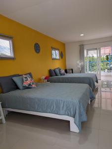 a bedroom with two beds and a yellow wall at La Bella Vista in Calarcá