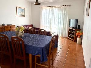 a dining room with a blue table and chairs and a tv at Casa do Cisne in Porto Santo