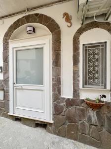 a white door and a window on a stone wall at Kupe Luxury Loft in SantʼAgata sui Due Golfi