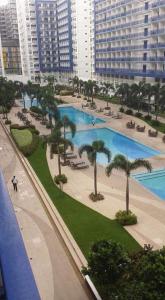 a large pool with palm trees in a city at CNholy Condo at SEA Residences in Manila