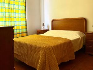 a bedroom with a bed with a yellow blanket on it at Casa do Cisne in Porto Santo