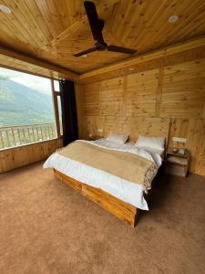 a bed in a wooden room with a ceiling fan at Aurora Grove in Manāli