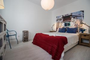 a bedroom with a large bed with a red blanket at Beach And Mountain Apartment in Sesimbra