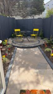 Dos sillas amarillas y una mesa en un patio trasero. en Peaceful Springfield Studio, en Chelmsford