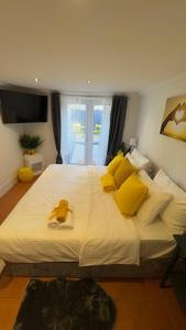 Un dormitorio con una gran cama blanca con almohadas amarillas. en Peaceful Springfield Studio, en Chelmsford