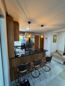 a kitchen with four bar stools and a counter at Casa Lençóis Maranhenses in Barreirinhas