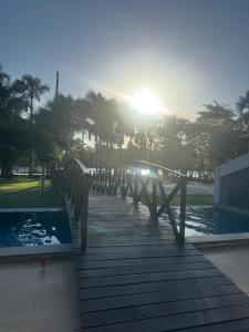 a bridge over a pool with the sun in the background at Casa Lençóis Maranhenses in Barreirinhas +6 photos