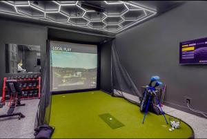 une salle avec un simulateur de golf avec un sol vert dans l'établissement Modern Dreamland in Old Town, à Scottsdale
