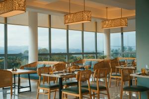 a restaurant with tables and chairs and large windows at Kandy Myst by Cinnamon in Kandy