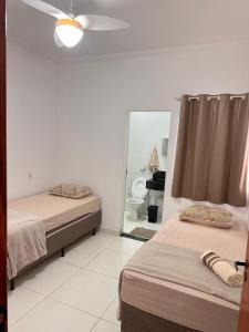 a room with two beds and a mirror and a bathroom at Espaço da Hospedagem H2 in Araxá