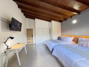 a bedroom with two beds and a desk and a tv at Laureles Boutique Stay in Medellín