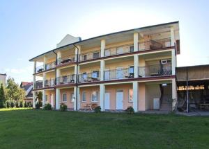 a large apartment building with a lawn in front of it at OW Wilk - pokoje i domki z aneksami kuchennymi, parking, plac zabaw in Łeba