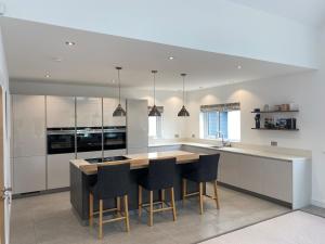 a kitchen with white cabinets and a island with bar stools at St Annes Coastal retreat in Cushendall