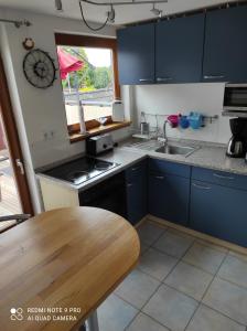 eine Küche mit blauen Schränken und einem Holztisch in der Unterkunft Haus Sonnenschein in Heikendorf + 4 Fotos