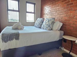 a bed in a room with a brick wall at 1 bed Apartment in hatfield in Pretoria