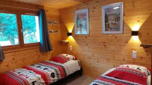 une chambre avec deux lits dans une cabane en rondins dans l'établissement Nouveau le Ské chalet, terrain clôturé, garage, animaux acceptés, proche lac, à Gérardmer