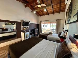 een hotelkamer met twee bedden en een televisie bij Mirante do Pirata in Ubatuba