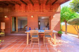 an outdoor patio with a wooden table and chairs at Villa with private pool 3 minutes from the beach in Montroig