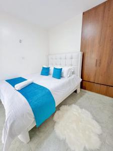 a white bed with blue and white pillows and a rug at Destiny homes in Rungiri