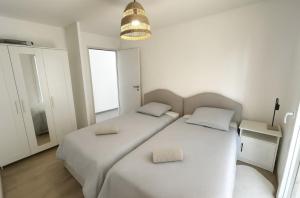 two beds in a white bedroom with a lamp at Maison de Standing 3 Chambres Parking Spacieux in Château-Gaillard
