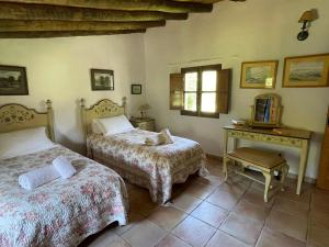 a bedroom with two beds and a desk and a window at La Casita de Platero in Los Marines