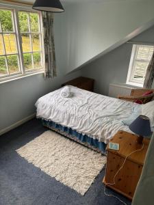a bedroom with a bed with a rug and two windows at Willow Cottage in Settrington