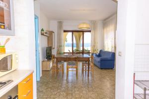 cocina y comedor con mesa y sofá azul en Caminia - La baia incantata, en Caminia 25 fotos más