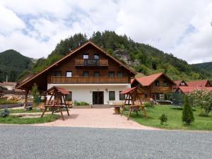 a large wooden house with a playground in front of it at Pensiune agroturistica Casa cu Povesti Rau Sadului in Rau Sadului