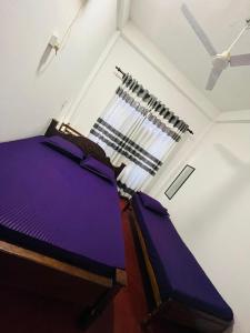 a bedroom with a purple bed and a window at Rathnayaka Family & Holiday Home in Anuradhapura