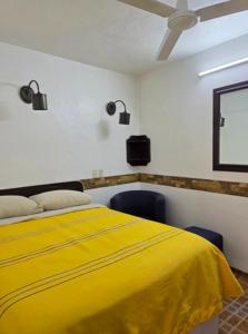 a yellow bed in a room with two chairs at Hotel Sauces Celaya in Celaya