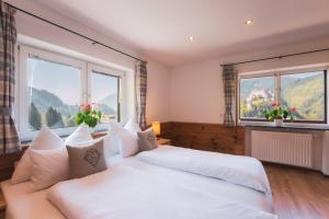 a bedroom with two white beds and two windows at Haus Biechl mit Blick auf die Burg Hohenwerfen in Pfarrwerfen