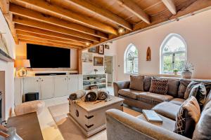 een woonkamer met een bank en een tv bij Castlemans Coach House in Sedlescombe