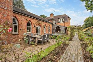 een stenen huis met een tafel en stoelen in de tuin bij Castlemans Coach House in Sedlescombe
