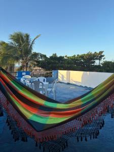 a rainbow hammock on a beach with tables and chairs at Casa Cochilo na Rede in Beberibe