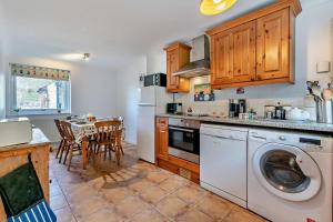 a kitchen with a washing machine and a table with chairs at Beachside Court in Porthtowan +14 photos