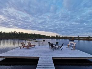 a wooden dock with chairs and tables on a lake at Siulakumpu Cabin in Inari