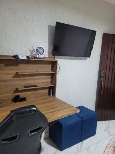 カボ・フリオにあるCantinho Submarino, aproximadamente 10 minutos caminhando até a praia do Forte, com Ar condicionadoの壁にテレビがあり、テーブルと青い箱が置かれている +18枚の写真