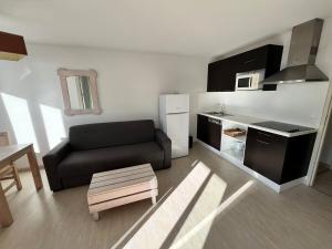 a living room with a black couch and a kitchen at Ocean Escape Mimizan Beach in Mimizan-Plage