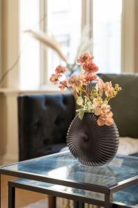 un jarrón con flores sentado en una mesa de cristal en Oslo Living, en Oslo
