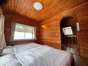 a bedroom with a bed in a wooden cabin at Lala's Riverside Cabin in Tsumagoi