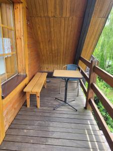 a wooden porch with a table and a bench on it at Pokoje Gościnne Grzegorz-2 in Białowieża