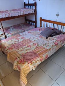 uma cama com uma colcha em cima em Toca da Suzara Suíte 1 até 4 pessoas Piscina Rio e Mar num só lugar em Florianópolis